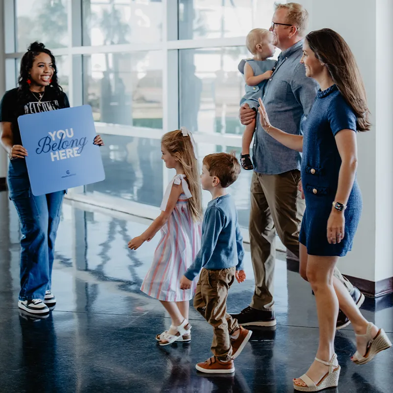 Church volunteer holding a sign that says 'You Belong Here'